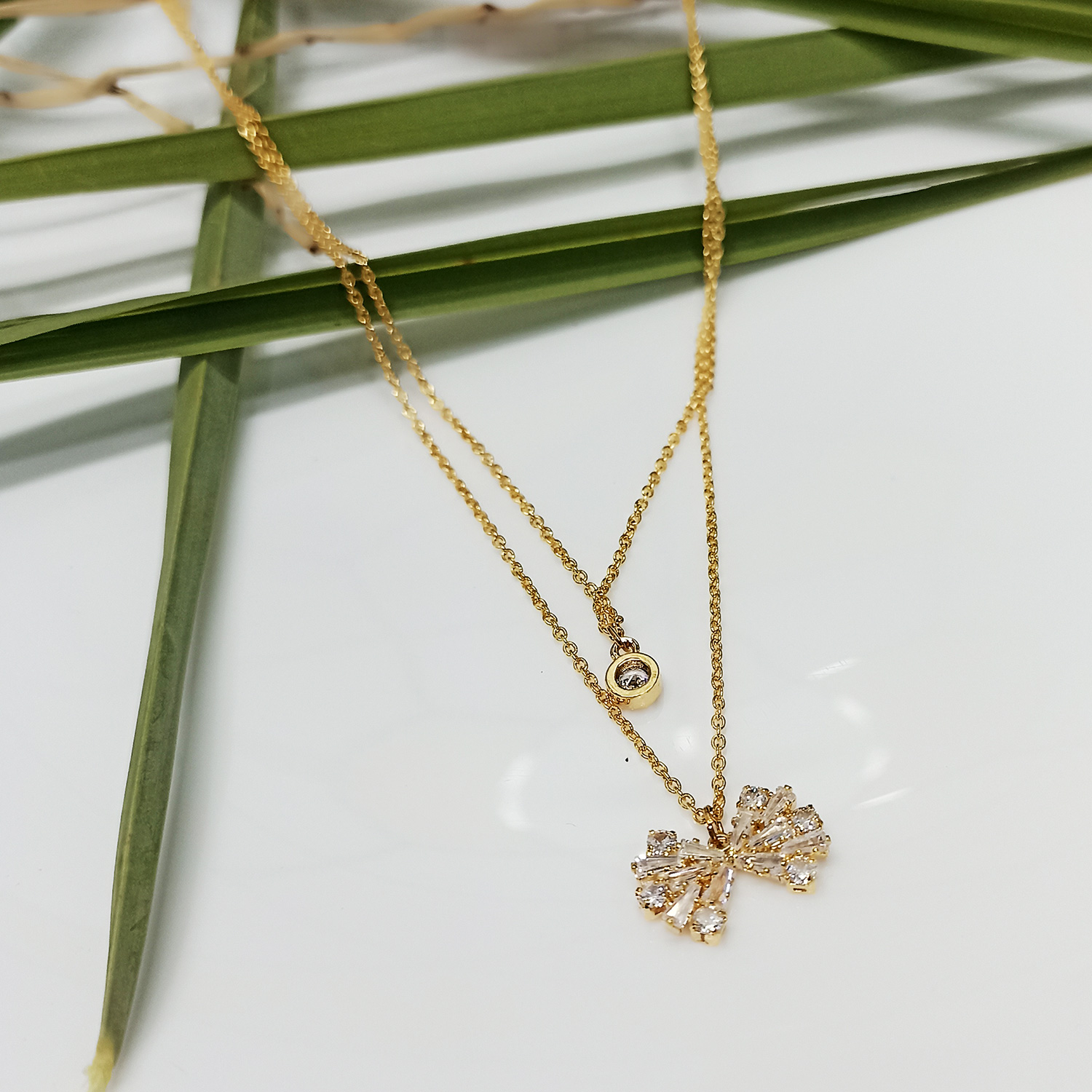 Layered Gold Necklace with Sparkling Bow and Solitaire Zircon Pendants
